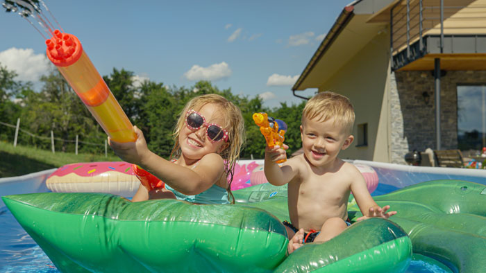 two children playing with squirt guns in pool
