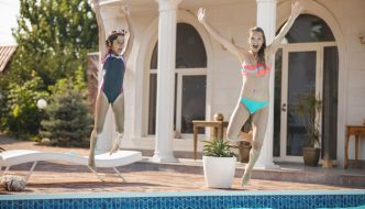 preteen girl and teen girl jumping into pool