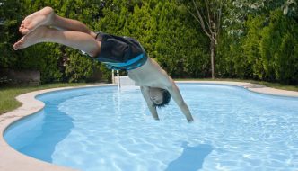 teen boy diving into kidney shaped swimming pool