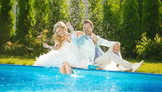 bride and groom splashing by pool