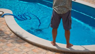 man vacuuming the bottom of his swimming pool