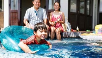 parents watching while child plays on inner tube in pool