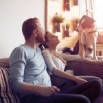 couple sitting on sofa talking to dog