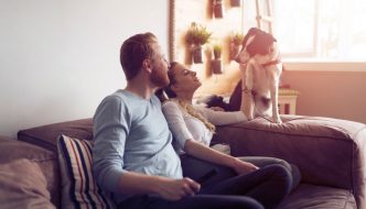 couple sitting on sofa talking to dog