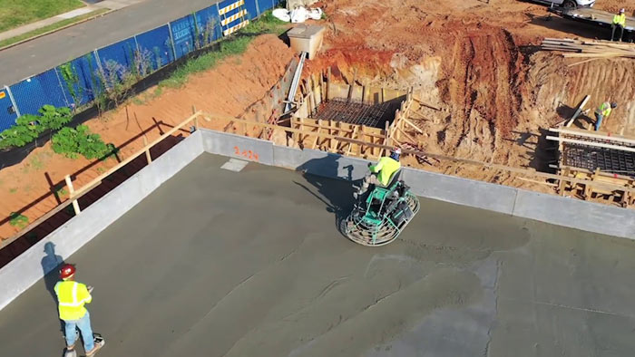 combs concrete crew flattening fresh concrete surface