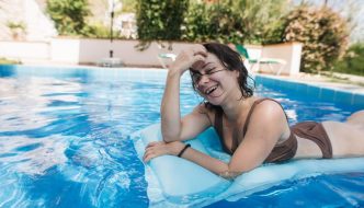 teen girl smiling floating on water in backyard pool