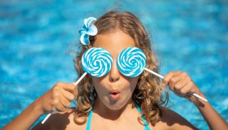 young girl with lollipops in front of pool