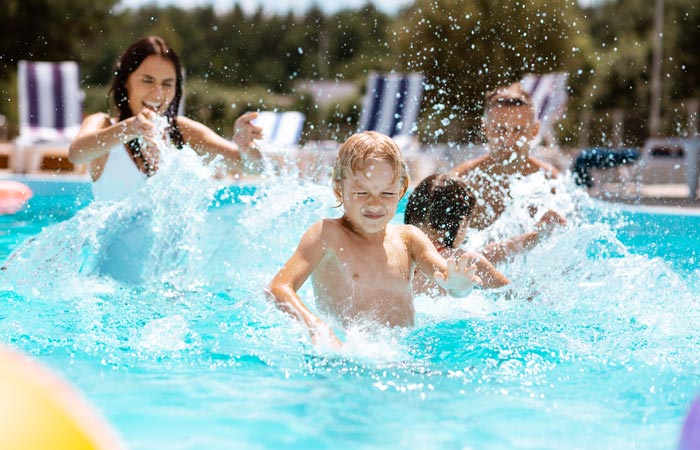 family splashing and having fun in swimming pool water