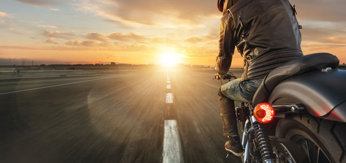 motorcyclist on highway riding off toward sunset
