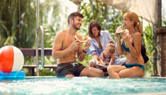 family and friends enjoying eating food around backyard pool