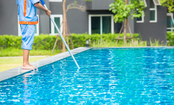 worker vacuuming the bottom of inground pool