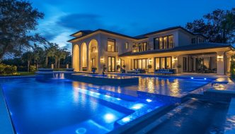 fancy estate house with inground pool at night