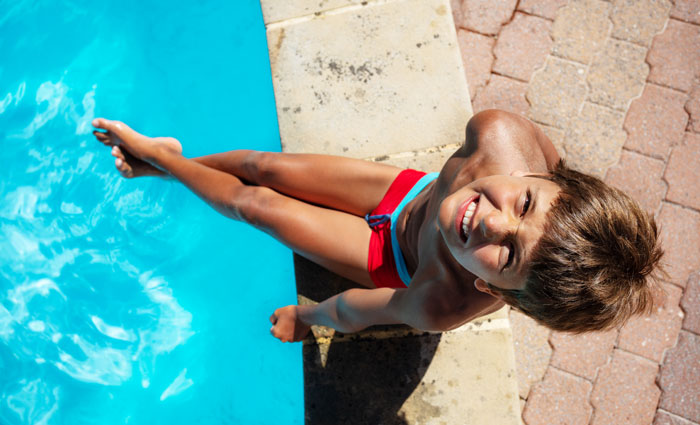 boy with all smiles sitting on pools edge